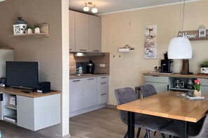 Eine moderne Küche mit Essbereich, Einbauküche, einer Kaffeemaschine und einem Fernseher auf einer Holzkonsole.