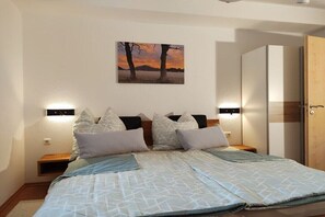Ein Schlafzimmer mit einem Bett, Kissen, einem Wandbild, Nachttischlampen und einem Kleiderschrank.