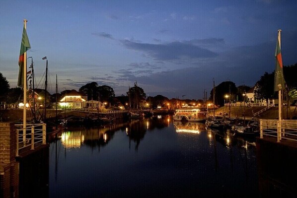 Ein Hafen an der Abenddämmerung mit ruhigem Wasser, Booten und Gebäuden mit Lichtern.