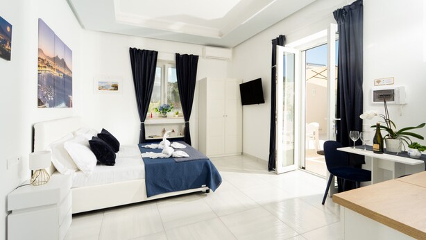 Una habitación de hotel moderna con cama, escritorio, silla, televisión y balcón.