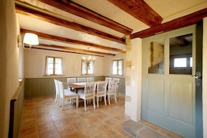 A dining area with a wooden ceiling, a light green door, and a tiled floor. - Holiday home Lindenhof (Pirna)