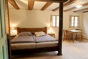 A bedroom with a four-poster bed, two bedside lamps, a wooden desk, and a chair. - Holiday home Lindenhof (Pirna)