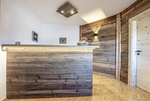 Ein Empfangsschalter mit Holzoptik, eine Wandleuchte und eine Tür auf der rechten Seite.