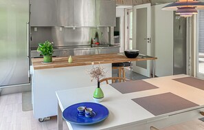 Eine moderne Küche mit einem Edelstahlkühlschrank, einer Holz Arbeitsplatte und einem Essbereich mit einem weißen Tisch und einem blauen Teller.