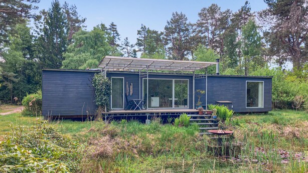 Een modern huis met een terras, grote ramen en een tuin.
