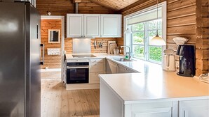 Una cocina moderna con armarios blancos, horno integrado y un amplio ventanal que proporciona luz natural.