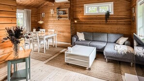 Interior acogedor de una cabaña con una mesa de comedor, sofá y una mesa de centro.