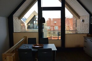 Ein Essbereich mit Tisch und Stühlen, ein Fenster mit Blick auf Gebäude und eine Tür.