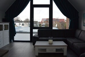 Ein Zimmer mit großem Fenster, einer Couch, einem Couchtisch und einem Schrank.