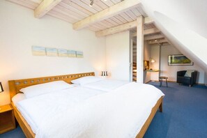 A bedroom with a large bed, wooden beams on the ceiling, a desk, and a chair. - Holiday apartment in Nebel with swimming pool (Nebel)