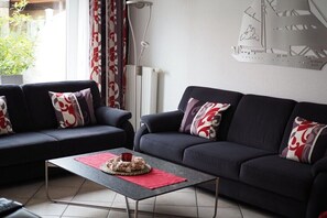 Ein Wohnzimmer mit zwei dunklen Sofas, einem Couchtisch und einer Heizung.