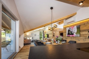 Eine moderne Küche mit Essbereich, Holzbalken und einem großen Fenster.