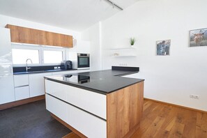 Eine moderne Küche mit weißen Schränken, einem Holzakzent, einer integrierten Kücheninsel und einem Fenster.