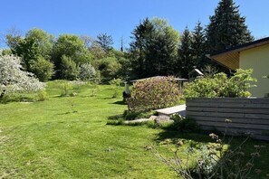 Ein gepflegter Garten mit Holzzaun, einer Bank und verschiedenen Bäumen und Sträuchern.