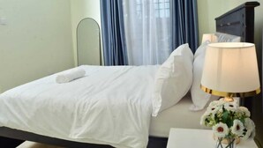 Ein Hotelzimmer mit einem Bett, einem Nachttisch mit Lampe und einer Blumenvase.