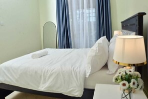 Ein Hotelzimmer mit einem Bett, einem Nachttisch mit Lampe und einer Blumenvase.