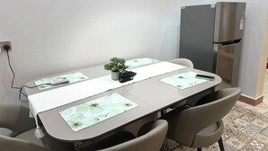 Ein Konferenzraum mit einem langen Tisch, Stühlen, einem kleinen Topf mit Pflanze und einem Kühlschrank.