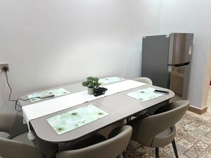Ein Konferenzraum mit einem langen Tisch, Stühlen, einem kleinen Topf mit Pflanze und einem Kühlschrank.