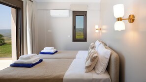 A hotel room with two beds, a view of the countryside, and a wall-mounted light fixture. - Alekos Beach Houses-Meliti Villa (Kefalonia)