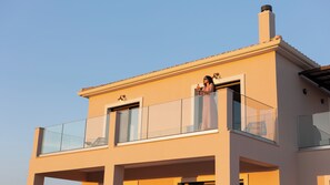 A modern two-story building with a balcony, large windows, and a chimney. - Alekos Beach Houses-Meliti Villa (Kefalonia)