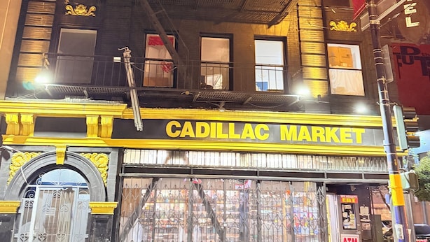 Een meerlaags gebouw met een winkelvoorgevel waarop 'Cadillac Market' staat.