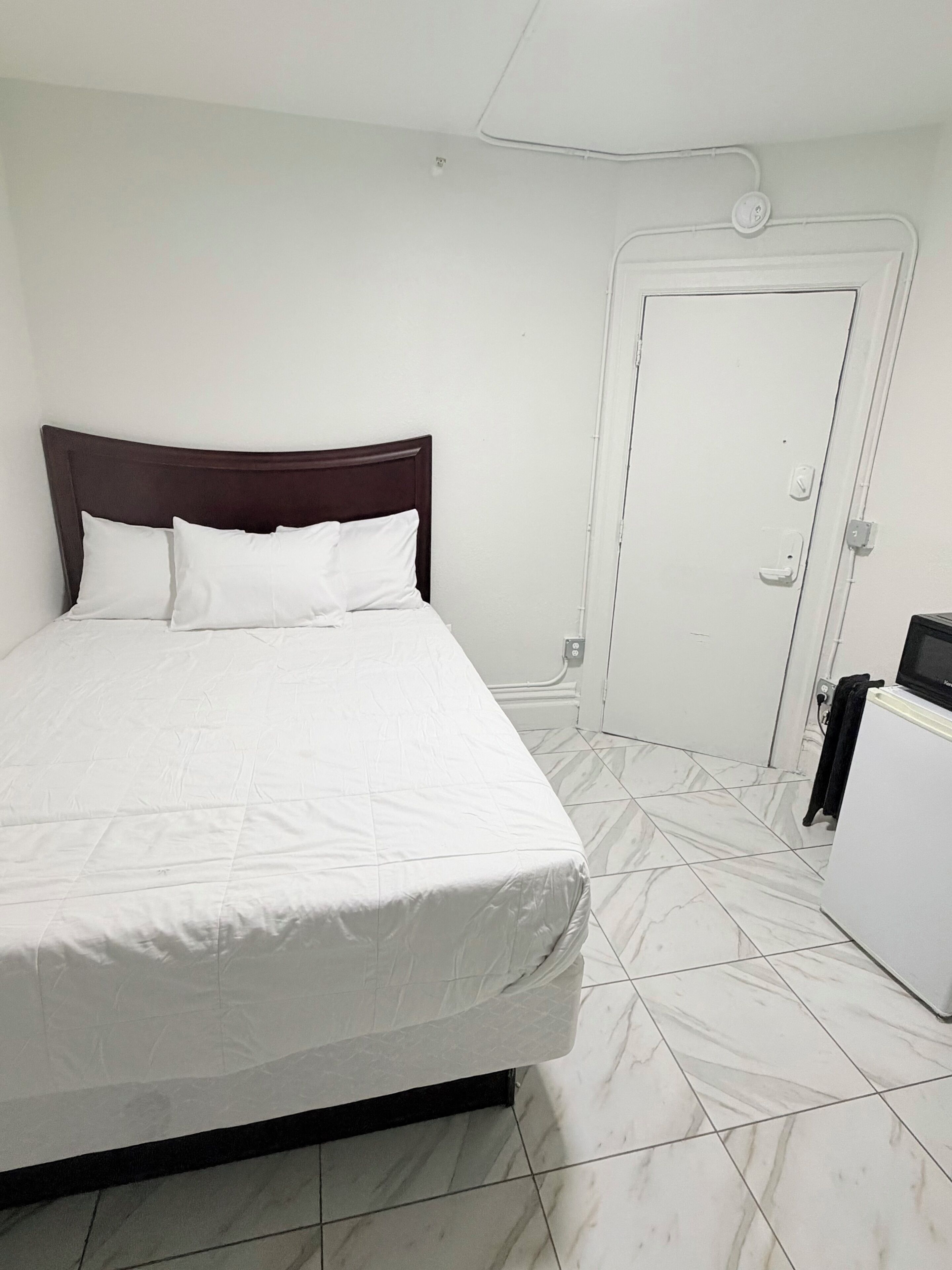 A room with a bed, a white door, and a white cabinet.