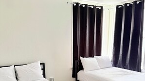 Twee enkele bedden met zwarte frames, witte beddengoed en een betegelde vloer.