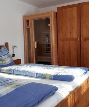 A bedroom with a bed, wooden wardrobe, and a door leading to a bathroom. - Holiday apartment with 2 bedrooms (Rauris)