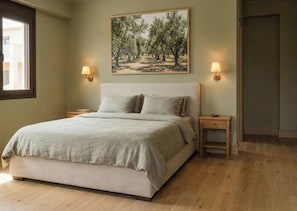 A bedroom with a bed, two bedside tables, a nightstand, a window, and a painting on the wall. - Alekos Beach Houses-Nereids Villas (Kefalonia)