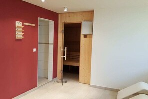 Ein Zimmer mit roter Wand, einer Holztür, einer Glaskabine und einem weißen Stuhl.