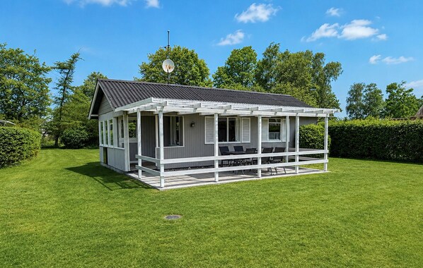 Ein eingeschossiges Haus mit Veranda, Satellitenschüssel und gepflegtem Rasen.