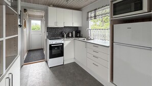 A compact kitchen with white cabinets, a stove, a microwave, and a refrigerator. - Nice home in Sydals with WiFi (Sydals)