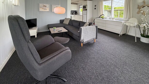 A modern living room with a grey sofa, a TV, a small table with a plant, and a kitchen area visible through an open door. - Nice home in Sydals with WiFi (Sydals)