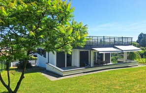 A modern house with a covered patio, a large tree in the foreground, and a clear blue sky. - Cozy home in Bassens with WiFi (Bassens)