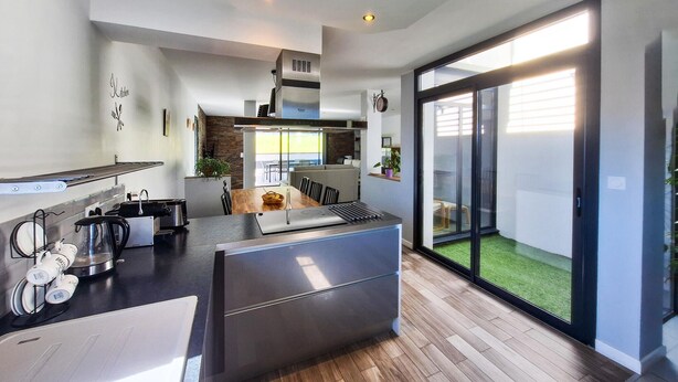 Una cocina moderna con comedor, un amplio ventanal corredera a un balcón y un espacio exterior visible.