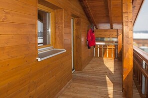 Eine Holzhütte mit einem Balkon, einem Fenster mit weißem Sims und einem Mantel, der an der Geländer hängt.