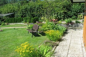 A garden with a bench, a pathway, and various plants. - Holiday apartment with 2 bedrooms (Niemetal)