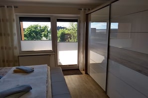A bedroom with a bed, a window, a sliding door, and a view of the outdoors. - Holiday apartment with 2 bedrooms (Niemetal)