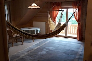 Eine Hängematte in einem Raum mit Tisch, Stühlen, einem Vorhangfenster und einer Heizung.