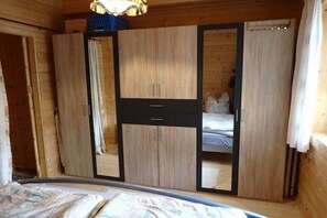 Ein Zimmer mit Holzboden, einem Bett, einem Kleiderschrank und einem Spiegel.