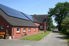 Ein rotes Backsteinhaus mit Solaranlage auf dem Dach, einer gepflasterten Auffahrt und einem Auto auf der Straße.