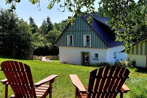 Ein Haus mit geneigtem Dach, einer Veranda und einem gepflegten Rasen.