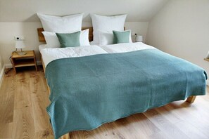 Ein Schlafzimmer mit einem Bett, Kissen, einem Nachttisch und Holzboden.