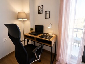Ein moderner Arbeitsraum mit Schreibtisch, Laptop, Stuhl, Lampe und zwei gerahmten Kunstwerken.