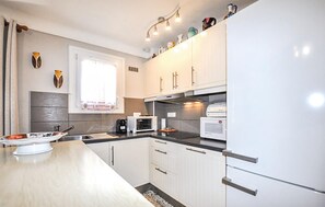 A modern kitchen with white cabinets, a black countertop, a built-in oven, and a microwave. - Stunning apartment in Argelès-Sur-Mer Plage (Argelès-Sur-Mer Plage)