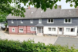 Ein zweistöckiges Wohnhaus mit roter Backsteinfassade und weißem Obergeschoss.