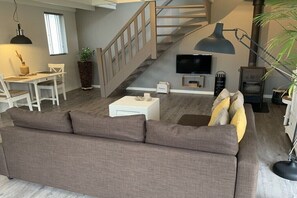 Ein modernes Wohnzimmer mit einer Couch, einem Esstisch, einem Fernseher und einem Kamin.