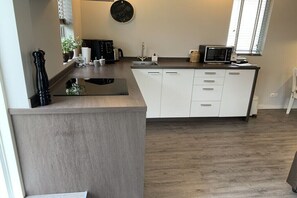 Eine moderne Küche mit integrierter Kochinsel, einer Mikrowelle und einer Kaffeemaschine.