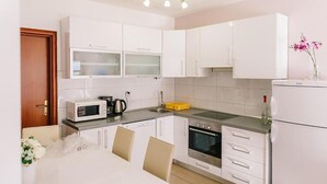 Een moderne keuken met witte kasten, een magnetron, een koffiezetapparaat en een spoelbak.
