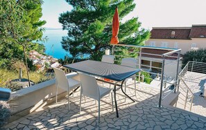 Eine Terrass mit Tisch und Stühlen mit Blick auf eine Küstenstadt und das Meer.